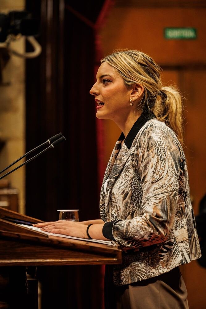 Andrea hablando en un atril con micrófono